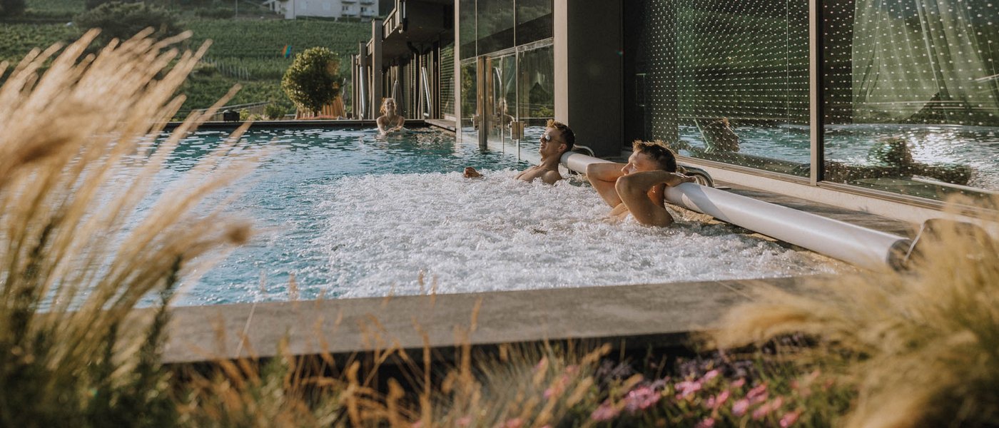 Hotel near Eppan an der Weinstraße: Gartenhotel Moser People relaxing in an outdoor pool next to a modern building with rural landscape