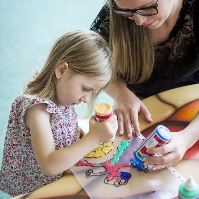 Familienhotels in Südtirol 4-Sterne-Superior Mädchen und Frau beim Ausmalen einer Zeichnung mit bunten Farben