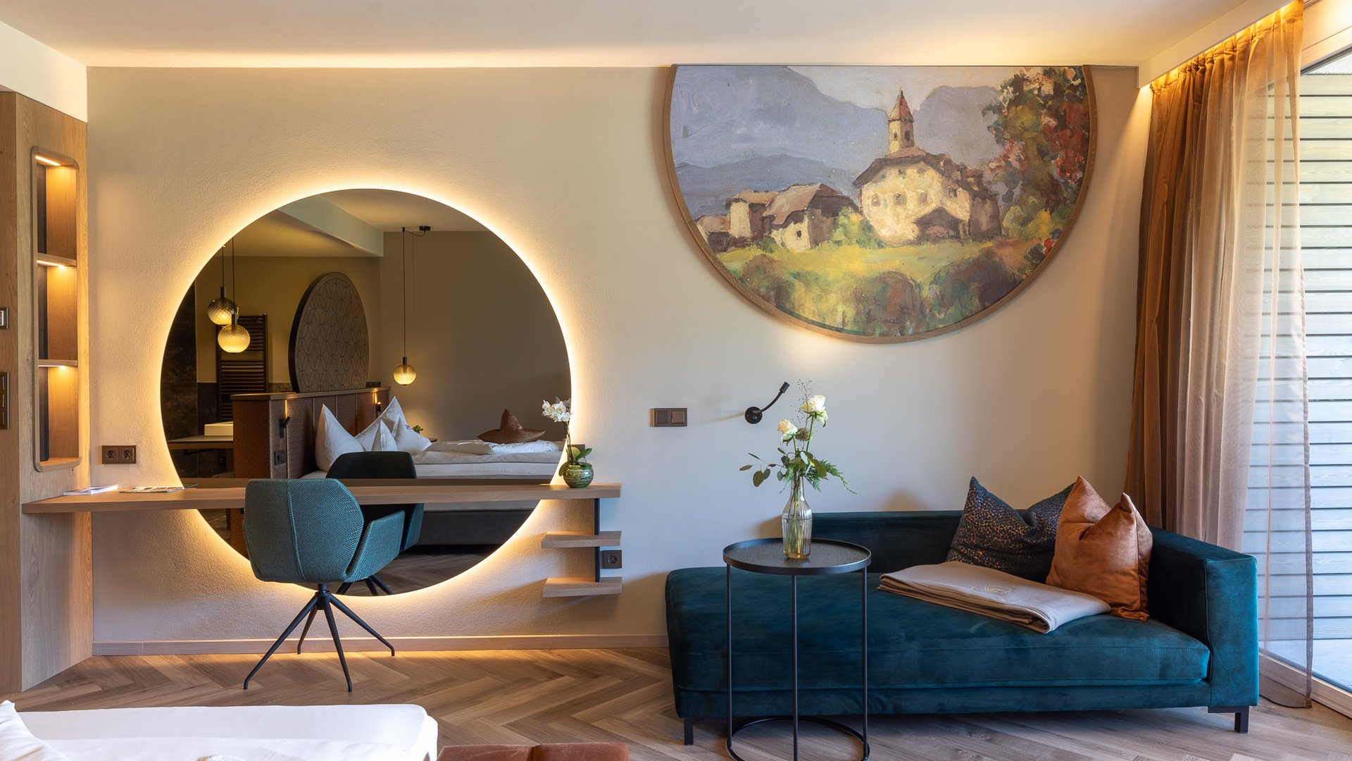 Hotels nahe dem Kalterer See 4-Sterne-Superior Modernes Wohnzimmer mit blauem Sofa, rundem Spiegel und Wandgemälde