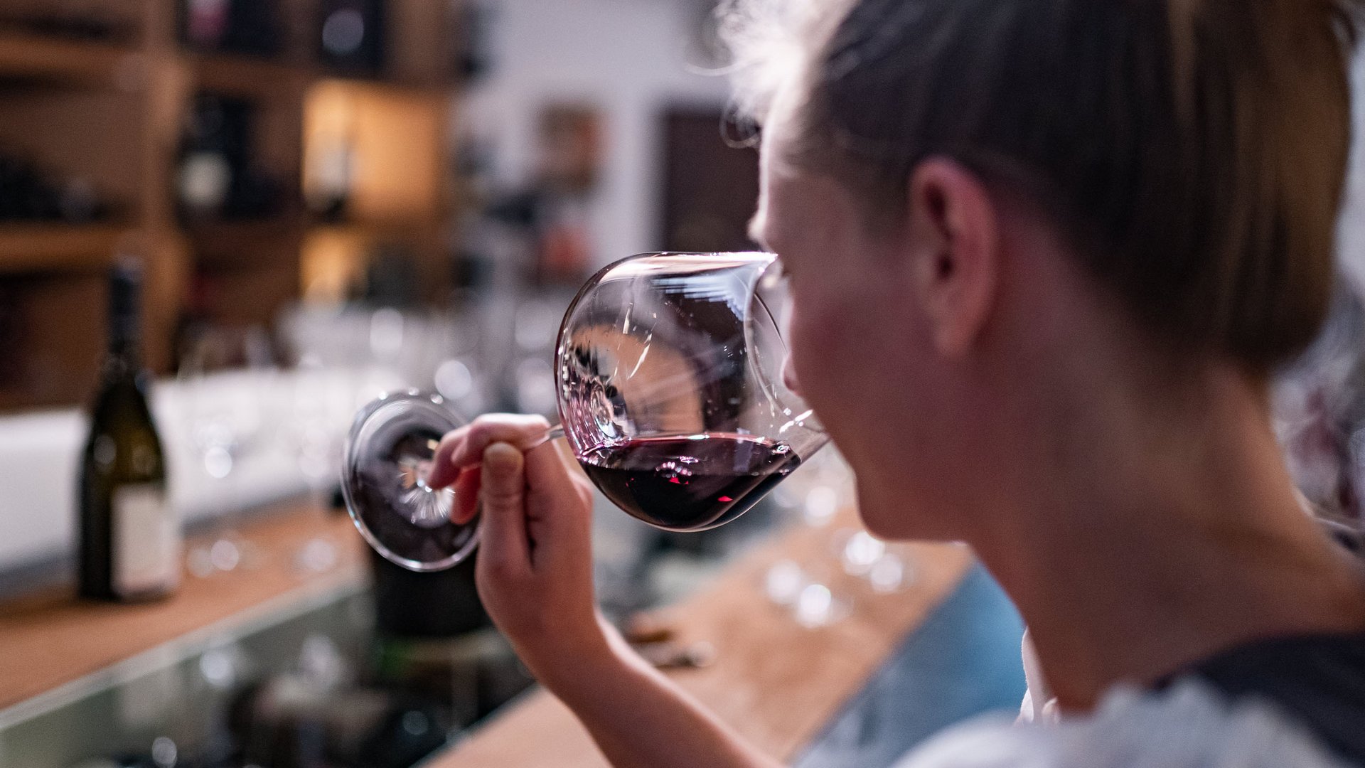 Gourmethotel in Südtirol: Gartenhotel Moser Frau riecht an einem Glas Rotwein in einer Bar oder Weinprobe