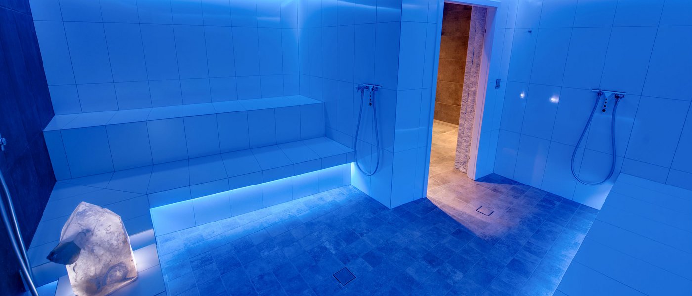 Wellness hotel with whirlpool and sauna world Modern steam room with blue LED lighting and white tiled bench seating