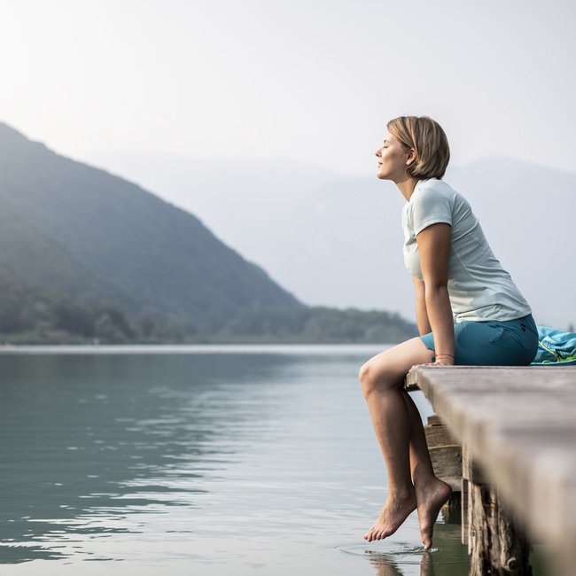 Hotel on Lago di Monticolo/Montiggler See: Gartenhotel Moser Woman sitting on dock enjoying the view of the lake and mountains