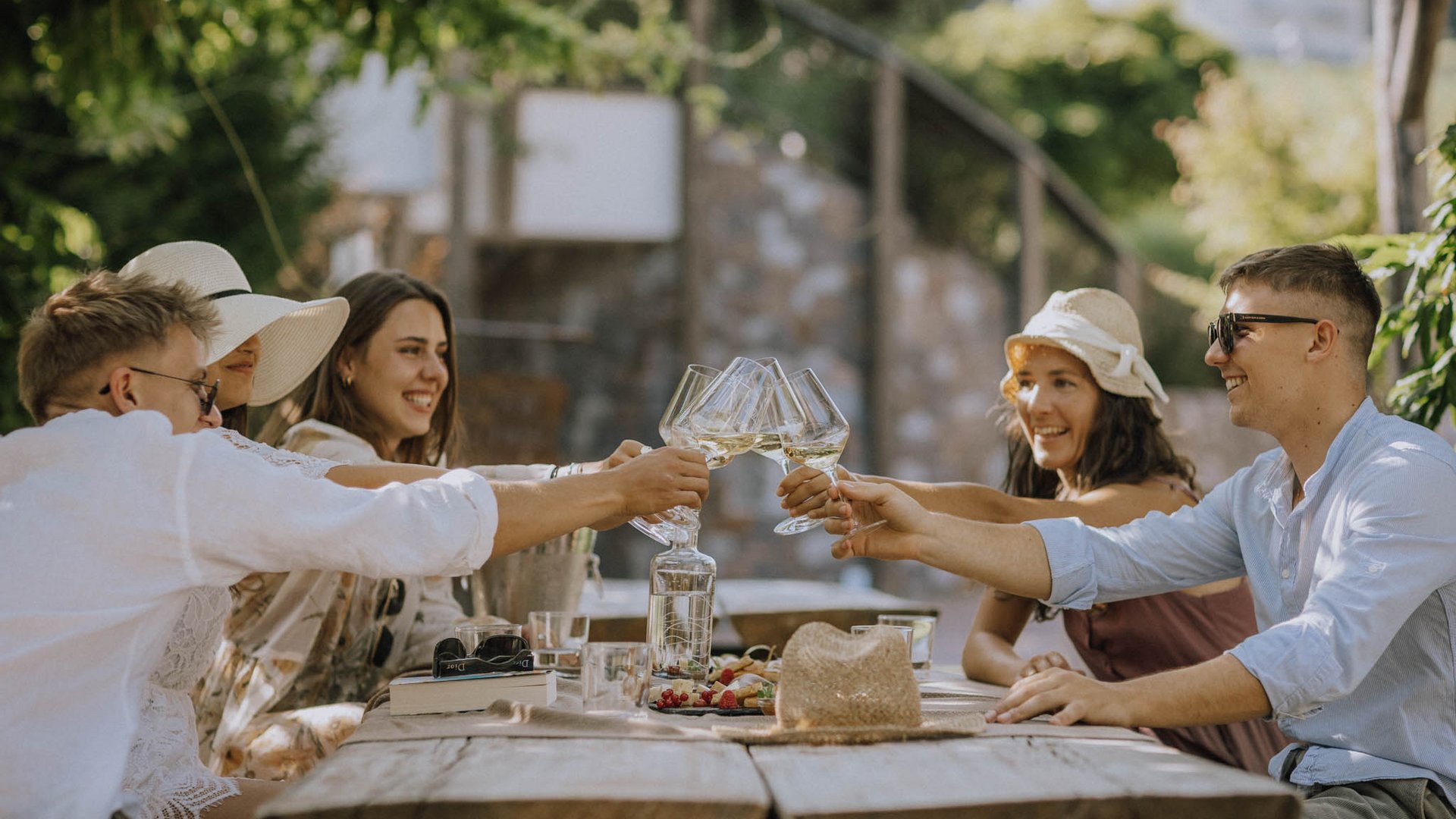 Hotel near Eppan an der Weinstraße: Gartenhotel Moser Six friends clinking wine glasses at a rustic wooden table outdoors