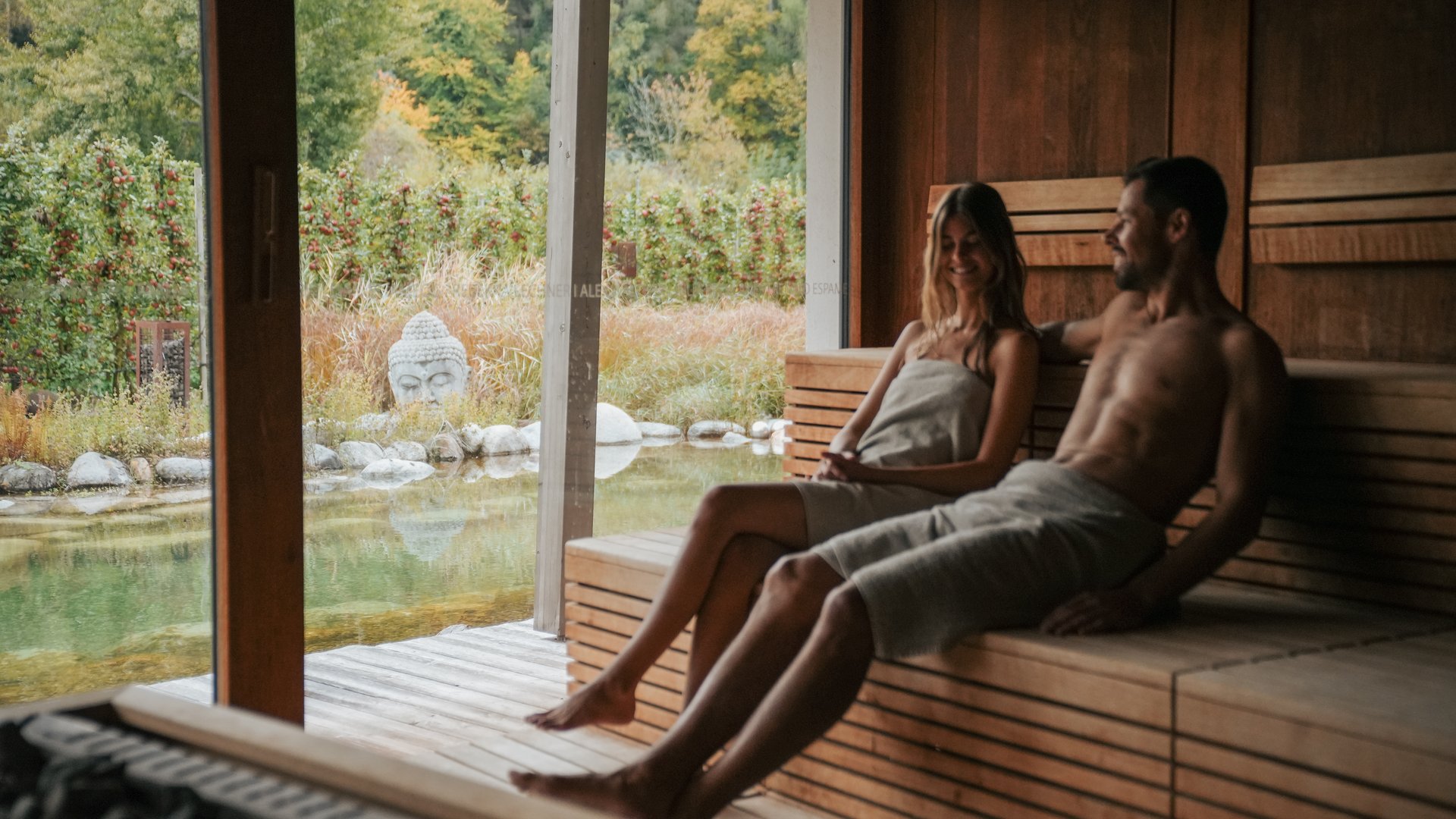 Hotels nahe dem Kalterer See 4-Sterne-Superior Paar entspannt in Sauna mit Blick auf Garten und Buddha-Statue
