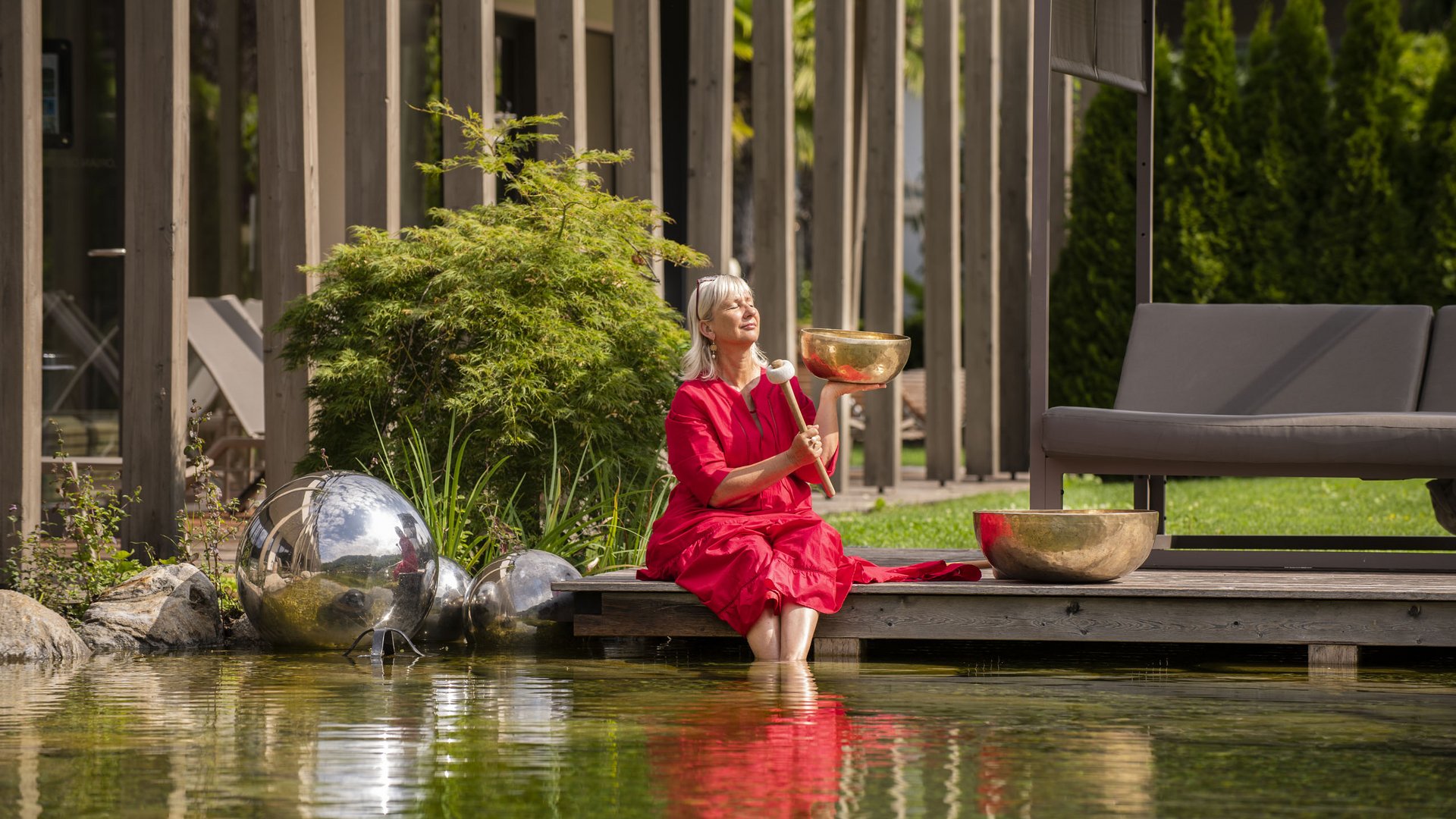 Hotel on Lago di Monticolo/Montiggler See: Gartenhotel Moser Woman in red dress sitting by pond playing a singing bowl