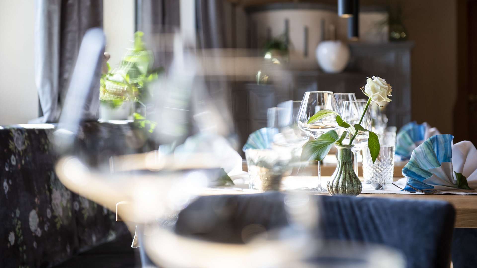 Gourmethotel in Südtirol: Gartenhotel Moser Tisch im Restaurant mit Weingläsern, weißer Rose und gefalteten Servietten