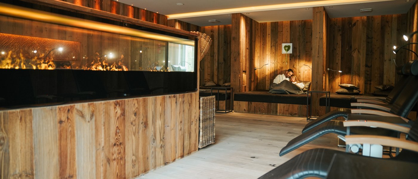 Wellness hotel with whirlpool and sauna world Cozy relaxation room with wood paneling, fireplace, and comfortable lounge chairs