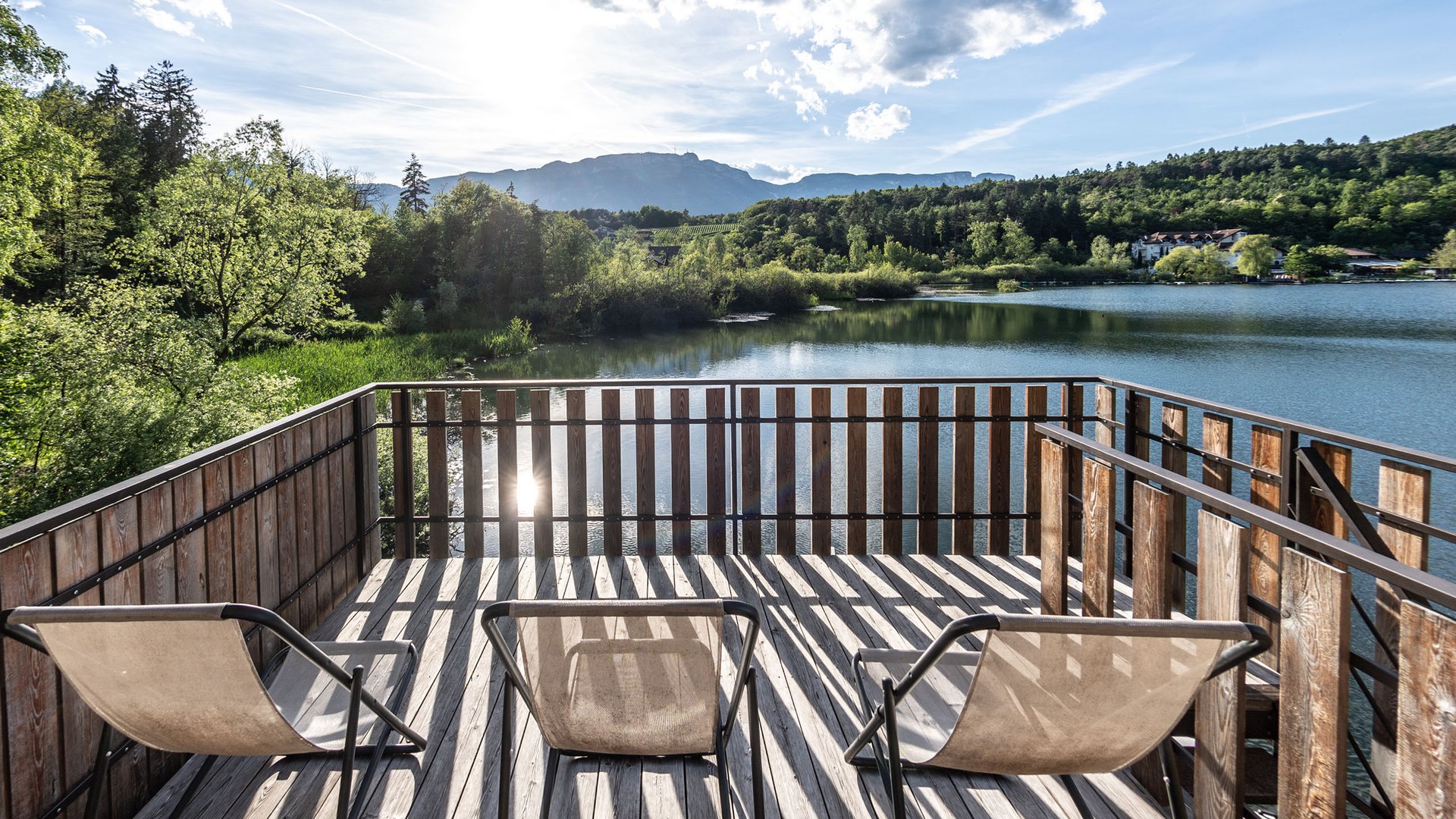 Wellnessurlaub am See: Gartenhotel Moser Drei Stühle auf Terrasse mit Blick auf See und Berge im Sonnenschein