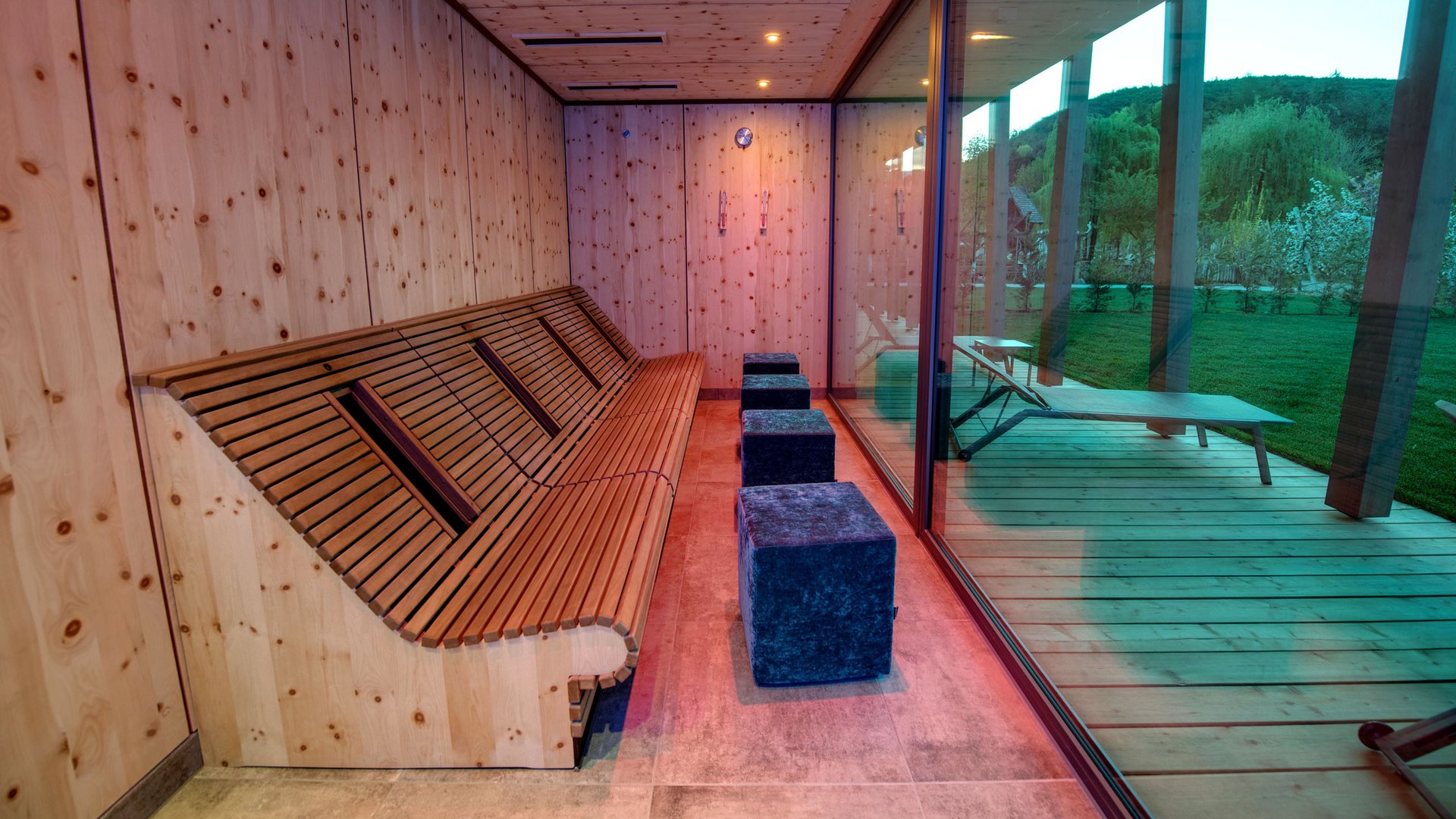 Wellness hotel with whirlpool and sauna world Modern relaxation room with wooden bench and glass wall overlooking outdoor terrace with lounge chair