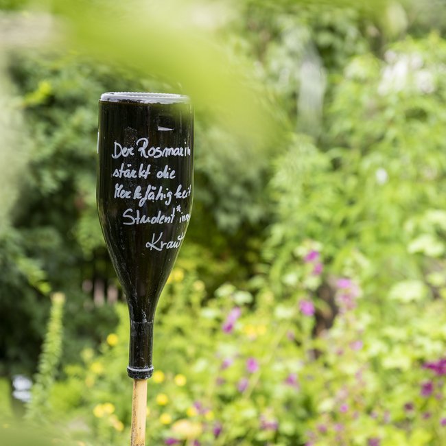 Lago di Monticolo/Montiggler See: a hotel that loves nature An upside-down wine bottle with German writing in a garden