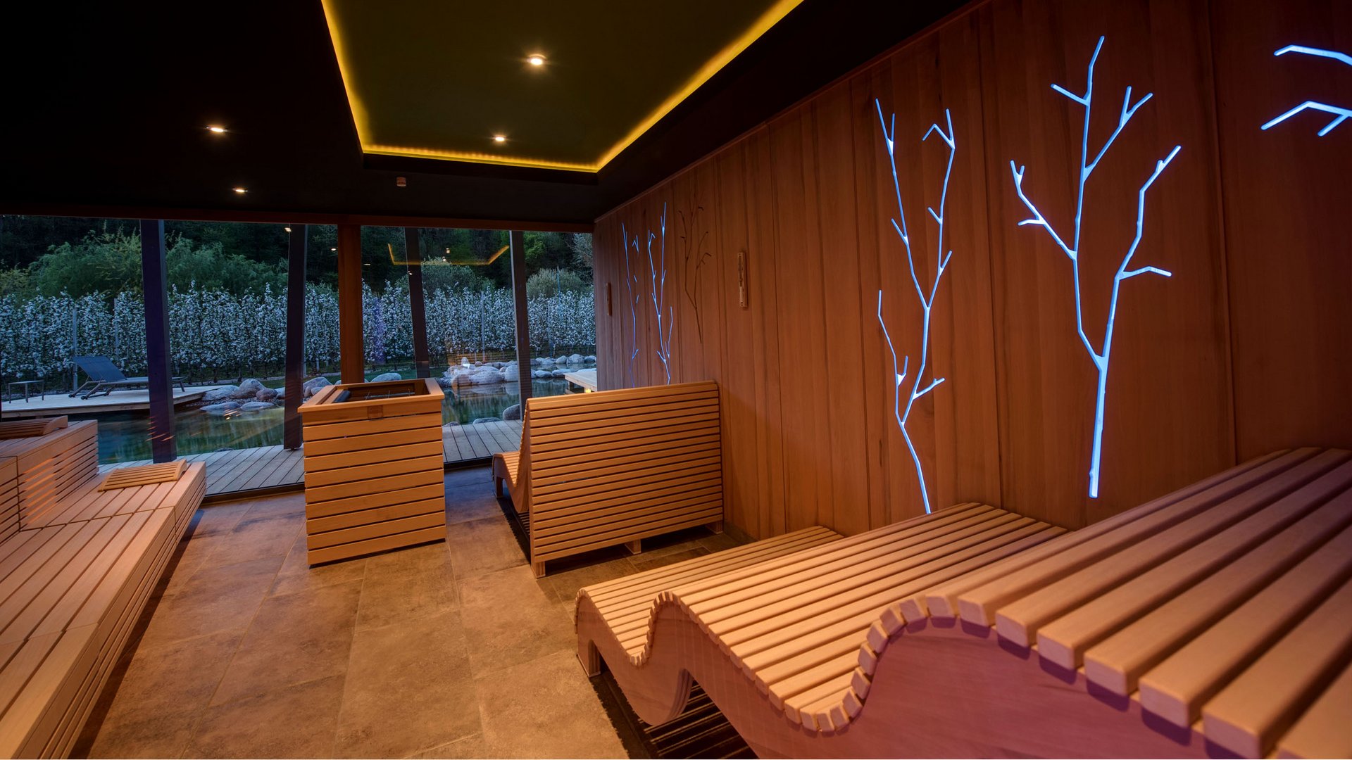 Hotel on Lago di Monticolo/Montiggler See: Gartenhotel Moser Modern sauna room with wooden loungers and blue tree-shaped light accents