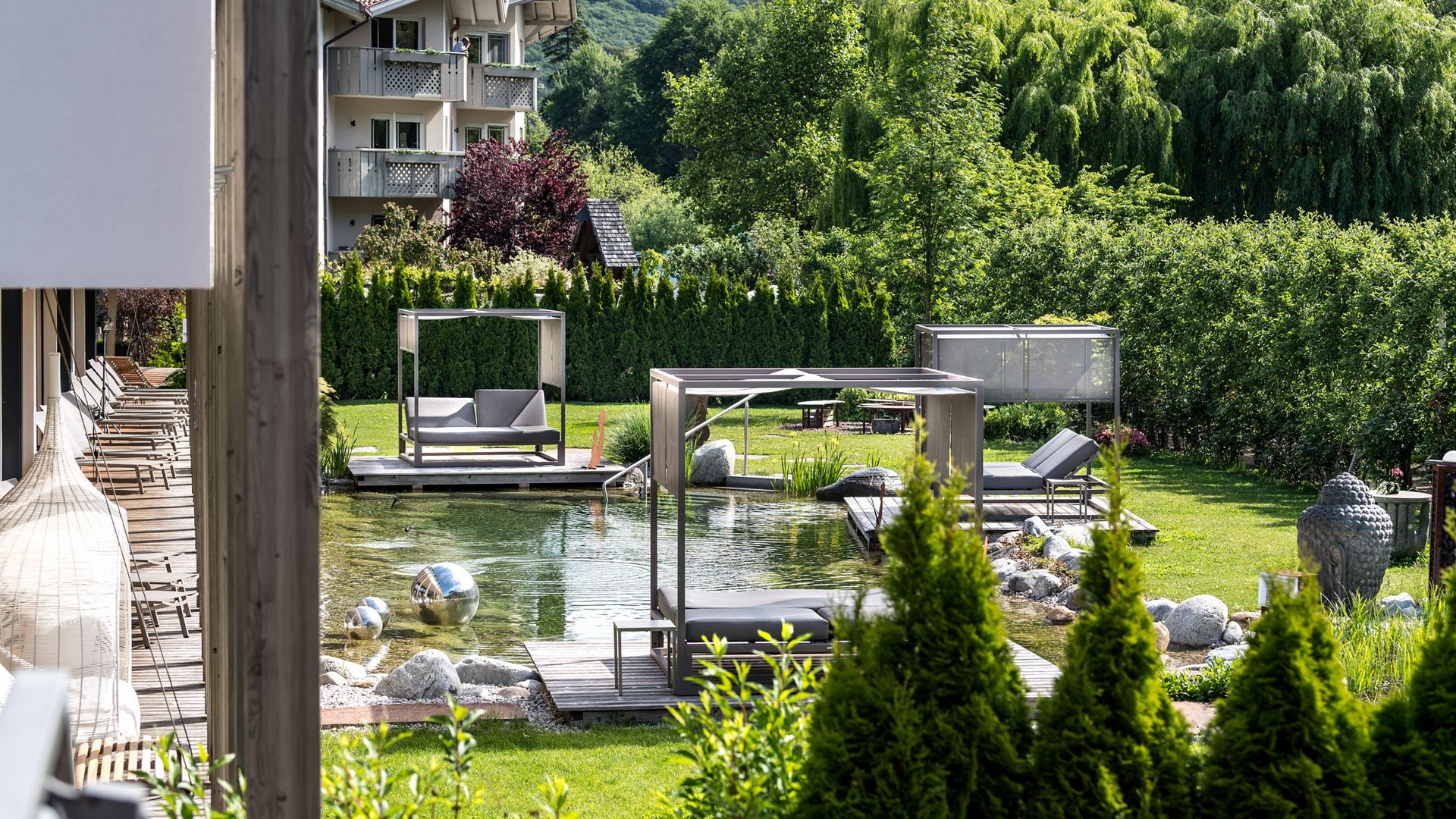 Hotel on Lago di Monticolo/Montiggler See: Gartenhotel Moser Modern garden furniture and pond in front of a building in a green landscape