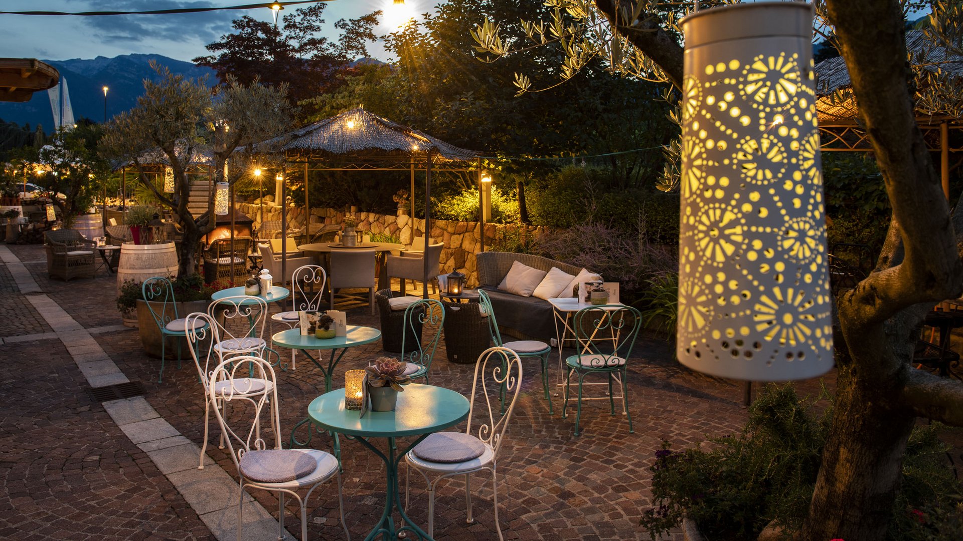 Gourmethotel in Südtirol: Gartenhotel Moser Abendliche Außenterrasse mit Tischen, Stühlen und dekorativer Beleuchtung