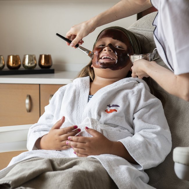 Hotel on Lago di Monticolo/Montiggler See: Gartenhotel Moser Child receiving a facial mask at a spa from a professional