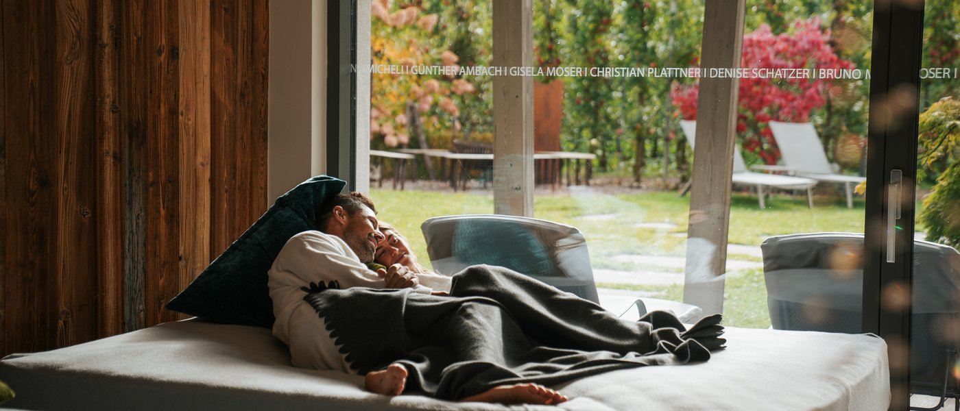 Wellness hotel with whirlpool and sauna world Couple relaxing on a bed by large glass door overlooking a garden