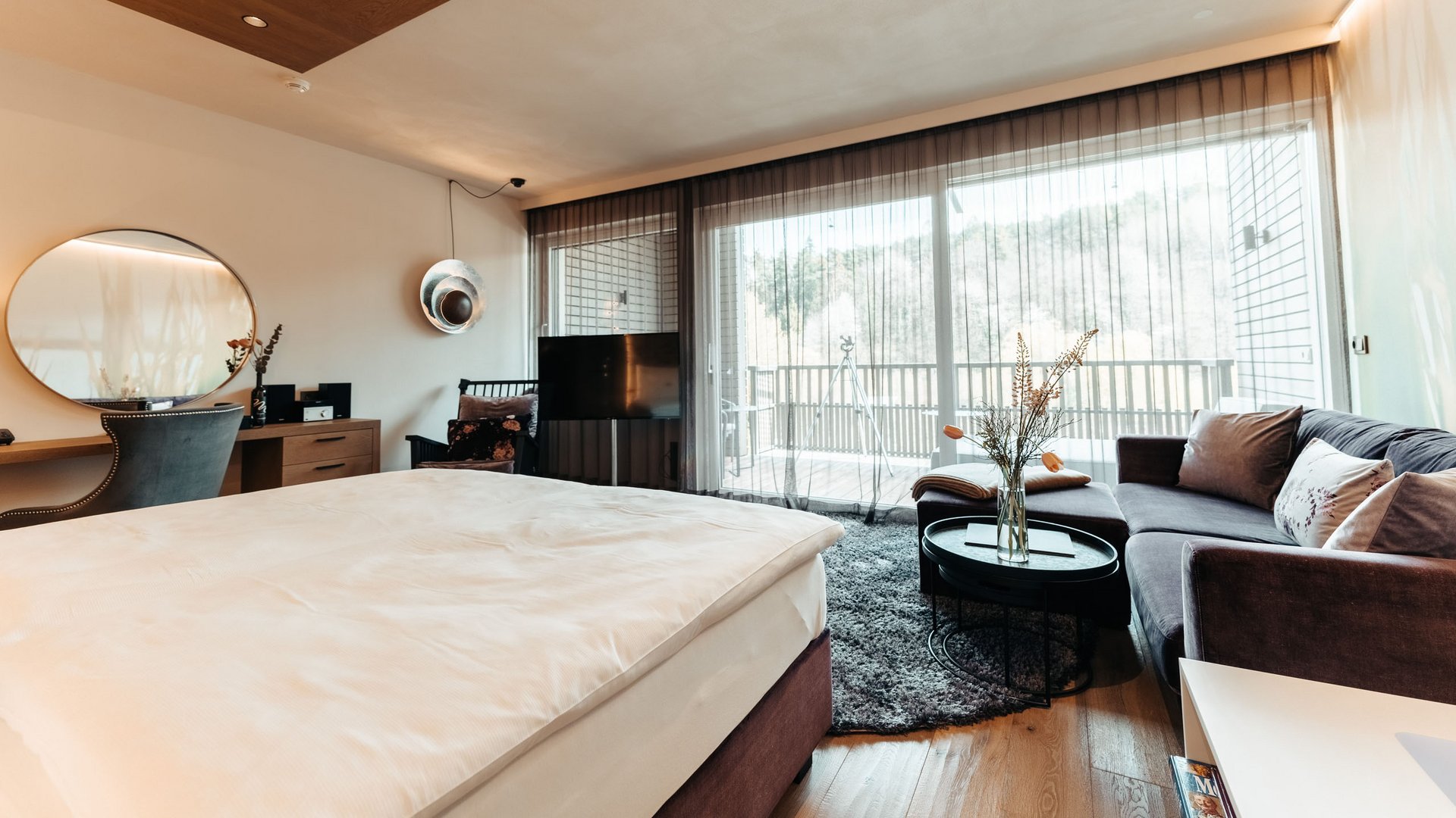 Hotel benessere in Alto Adige: posizioni Camera d'albergo moderna con letto, divano e ampia finestra sulla terrazza