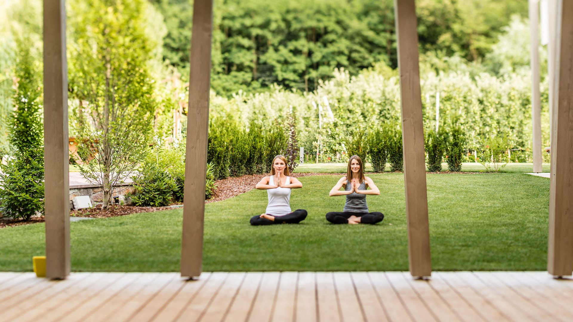 Hotel on Lago di Monticolo/Montiggler See: Gartenhotel Moser Two women practicing yoga on grass in a garden